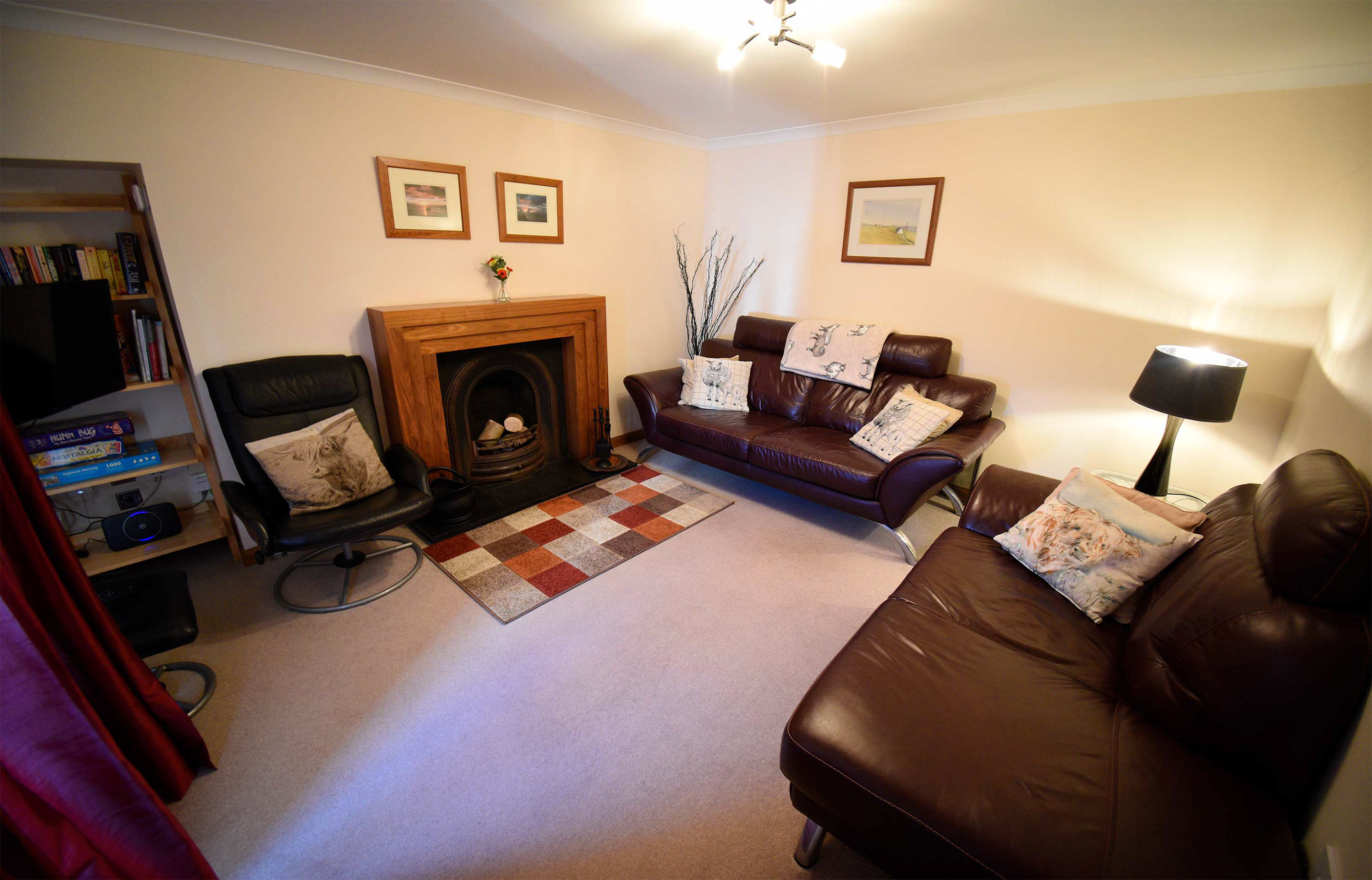 Relax and unwind in Aird Cottage living room with open fireplace and widescreen TV